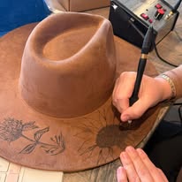 "Oakley" - a gorgeous brown, hand burned hat with flowers.
