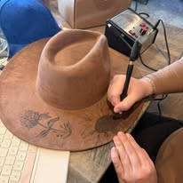 "Oakley" - a gorgeous brown, hand burned hat with flowers.